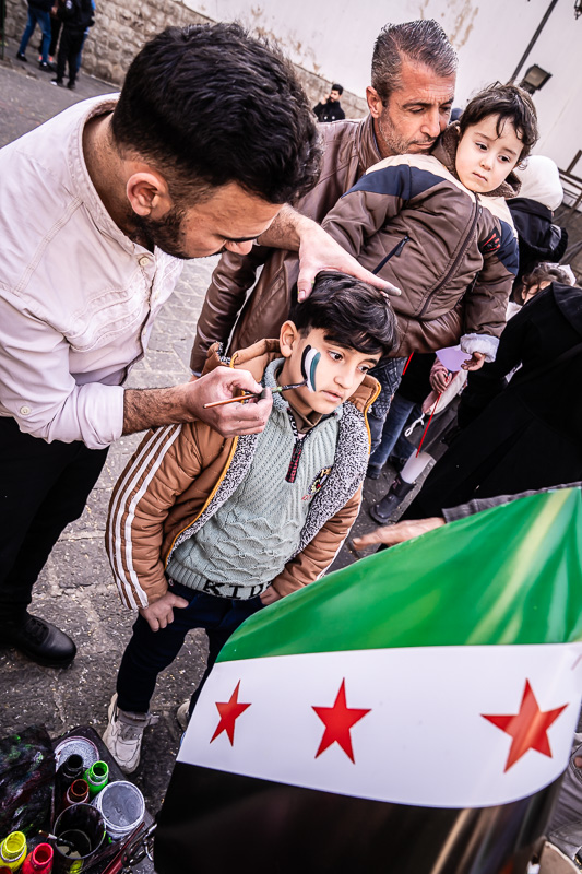 Street-Fotoreise Damaskus: Umayyaden-moschee. Geschäftstüchting: Kinder bekommen die Farben der neuen Fahne auf die Wangen gemalt.